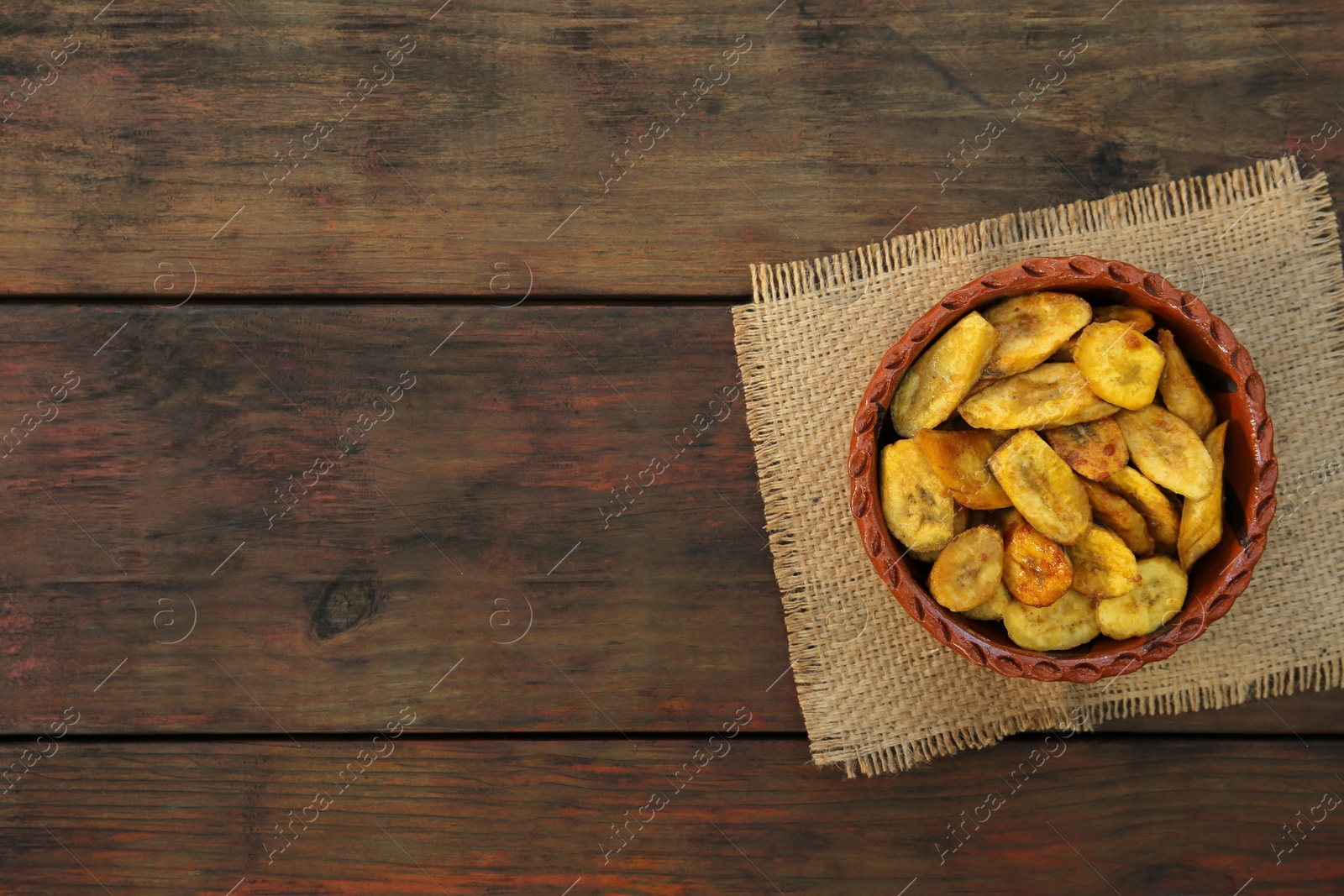 Photo of Tasty deep fried banana slices on wooden table, top view. Space for text