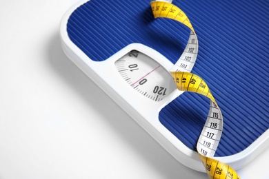 Photo of Modern scales and tape measure on white background, closeup view