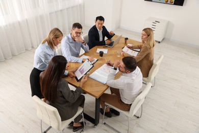Businesswoman showing chart on meeting in office, above view