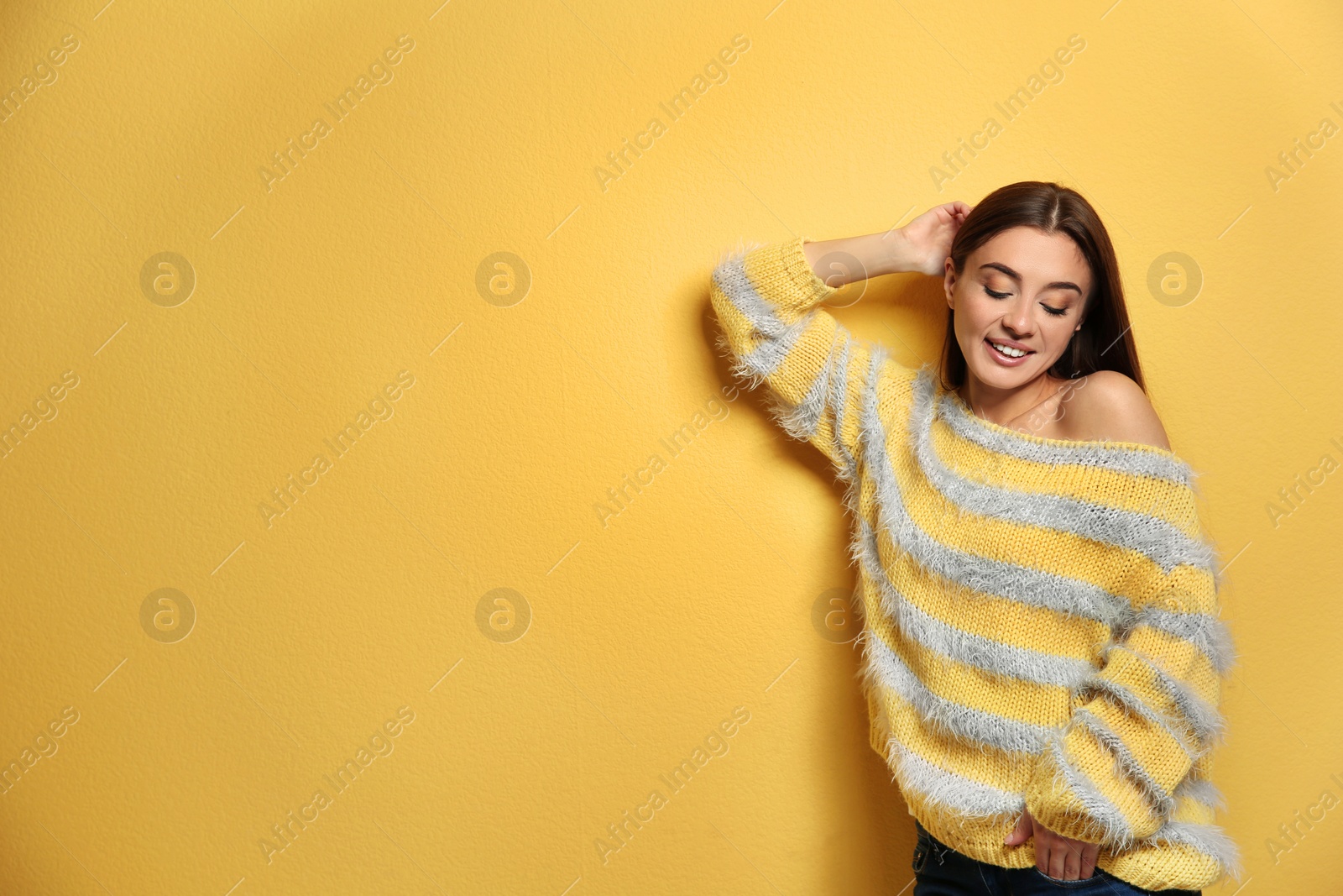 Photo of Beautiful young woman in warm sweater on color background. Space for text