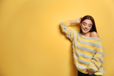 Beautiful young woman in warm sweater on color background. Space for text