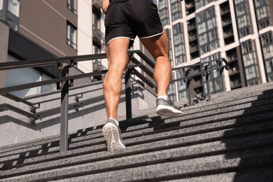 Man running up stairs outdoors on sunny day, closeup. Space for text