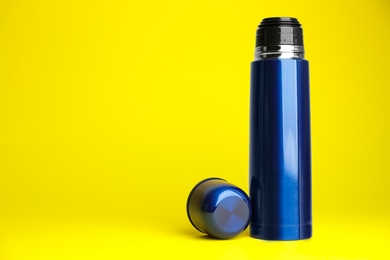 Photo of Stylish thermo bottle on yellow background, space for text