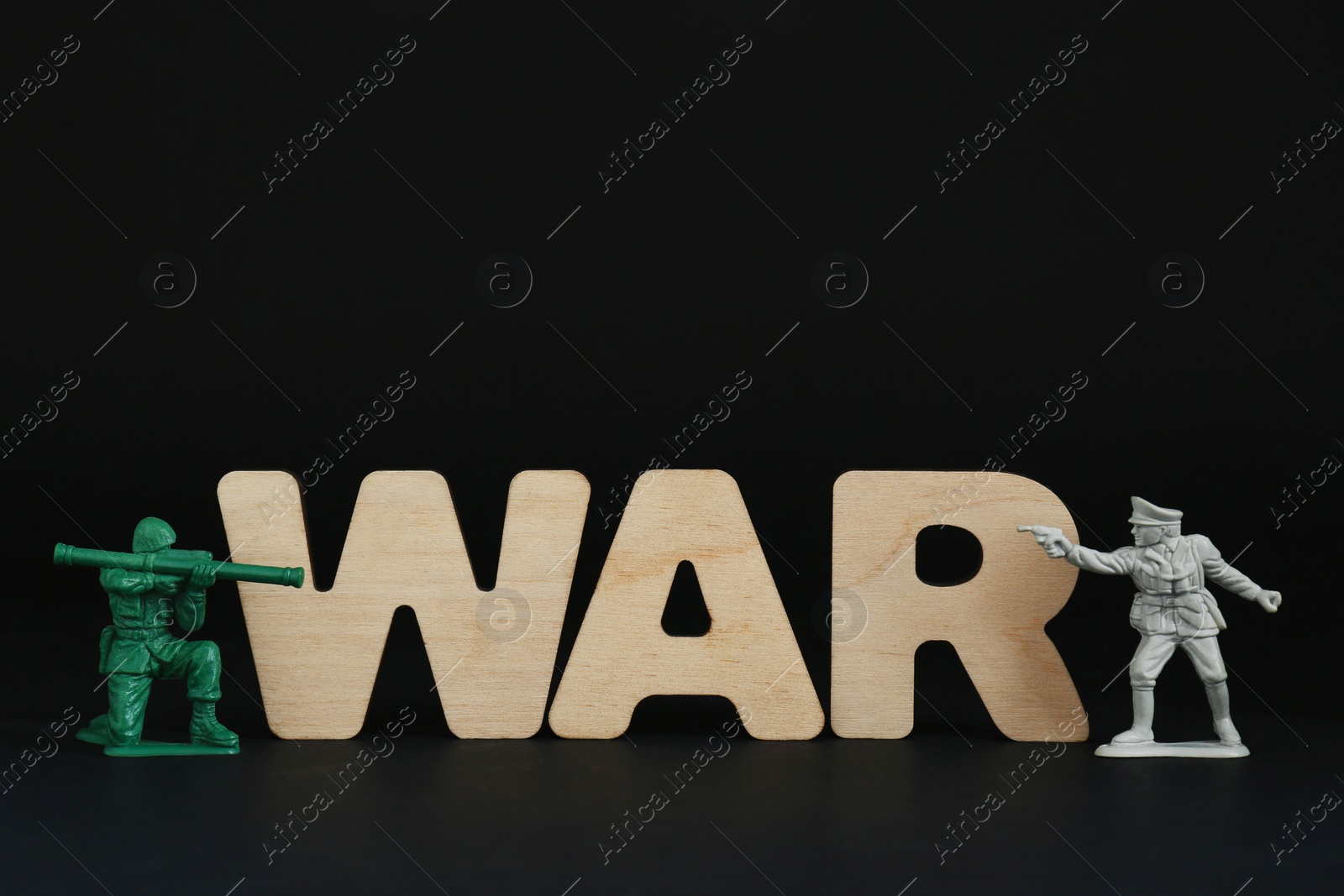 Photo of Word War made of wooden letters and toy soldiers on black background