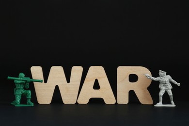 Word War made of wooden letters and toy soldiers on black background