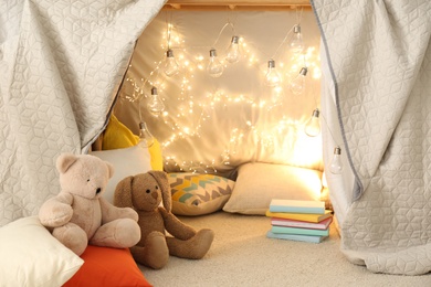 Play tent with toys and pillows indoors, closeup. Modern children's room interior