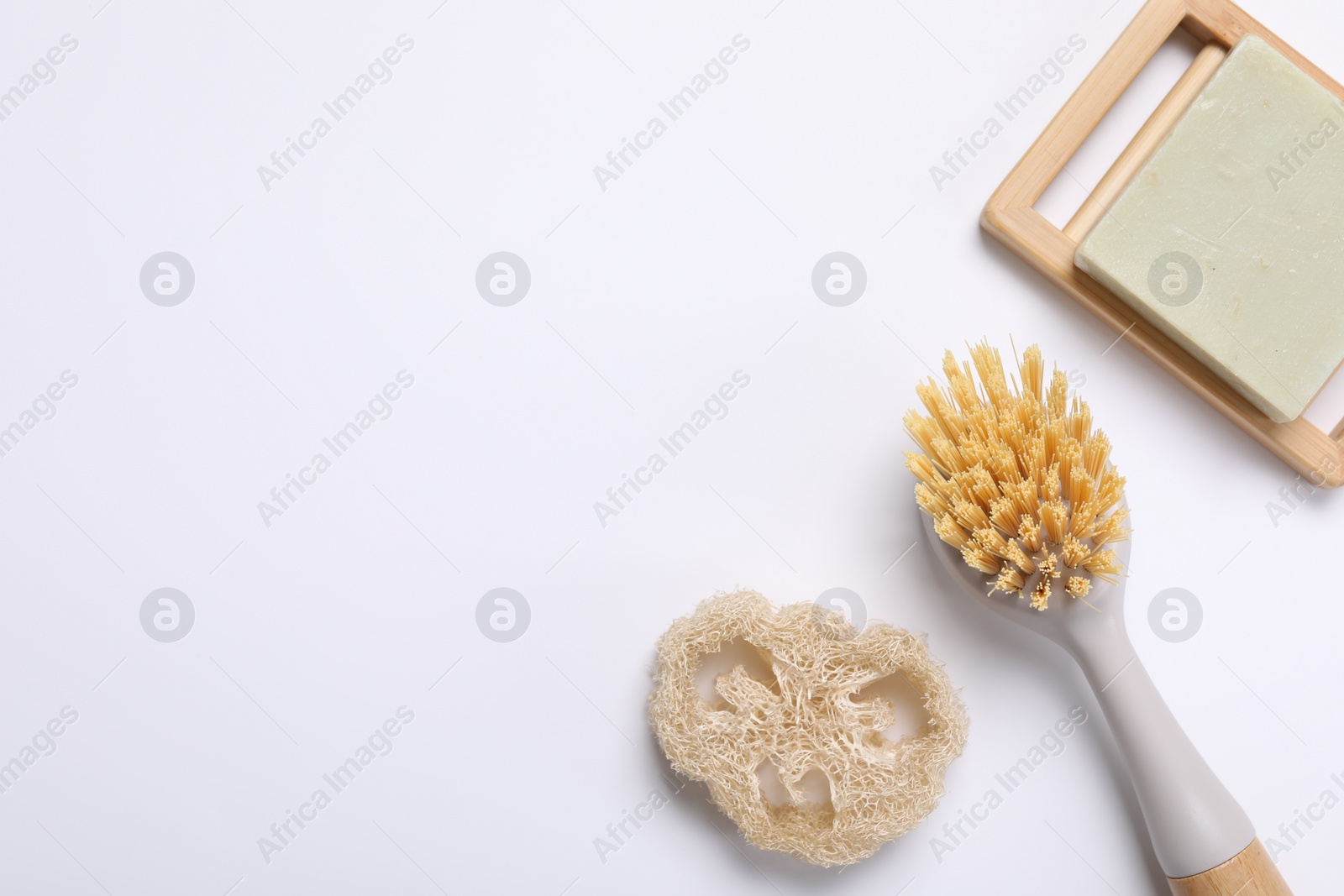 Photo of Cleaning brush, soap bar and loofah on white background, flat lay. Space for text