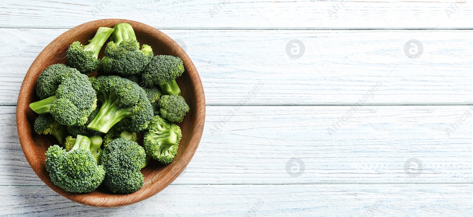 Image of Top view of fresh green broccoli on white wooden table, space for text. Banner design 