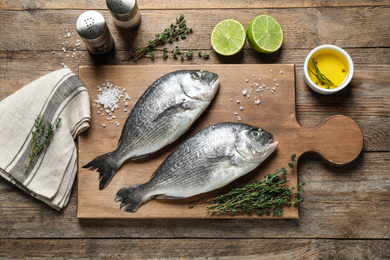 Photo of Flat lay composition with raw dorada fish on wooden table