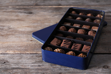 Photo of Metal box with tasty chocolate candies on wooden table