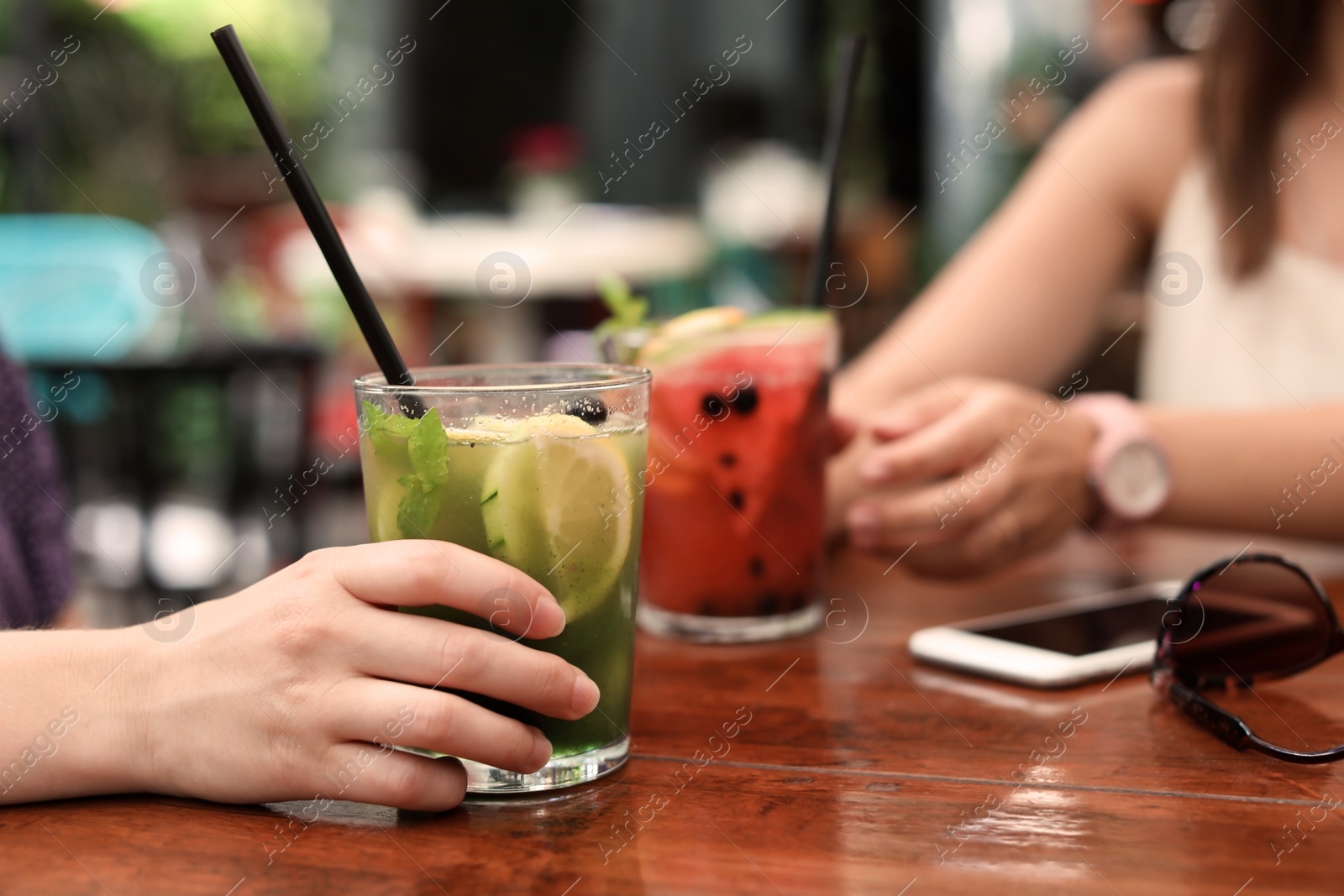 Photo of Women with glasses of tasty lemonade at table, closeup