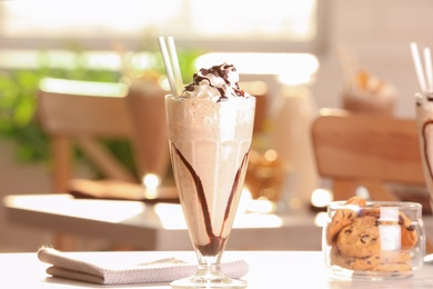 Glass with delicious milk shake on table indoors