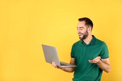 Photo of Man using laptop for video chat on color background. Space for text