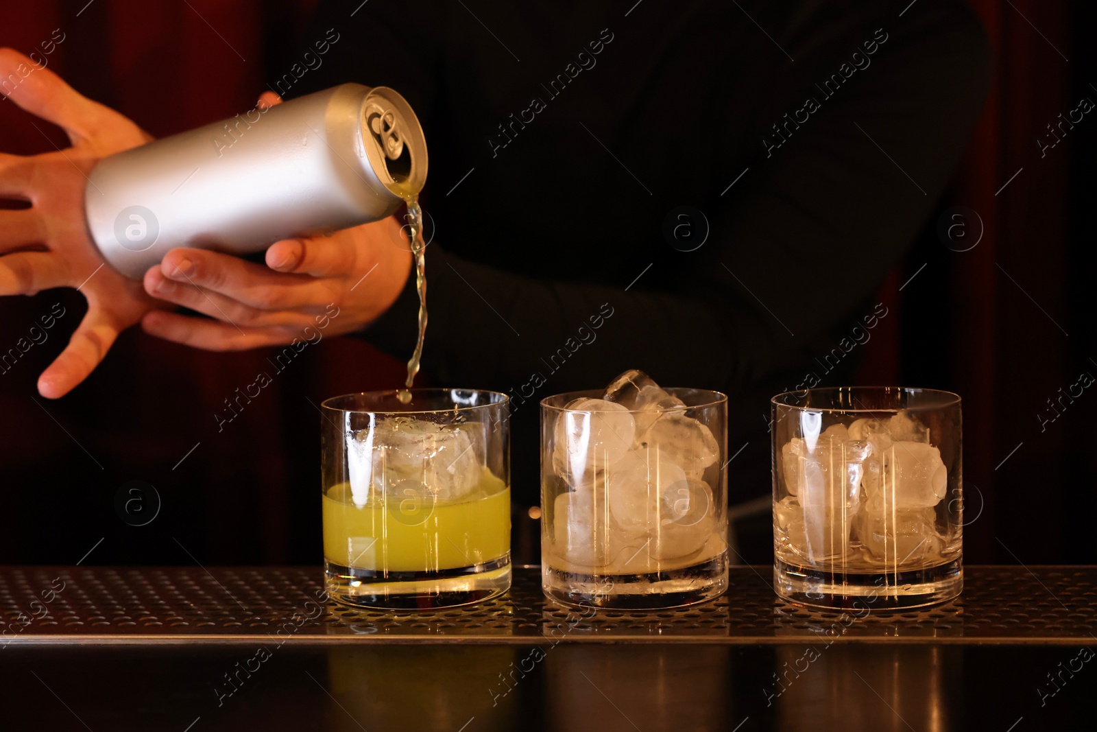 Photo of Bartender pouring energy drink into glass at counter in bar, closeup