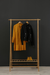 Photo of Rack with stylish clothes near black wall