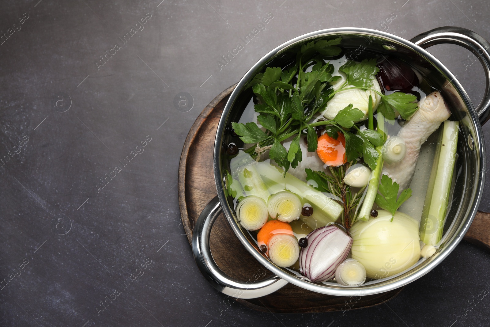 Photo of Different ingredients for cooking tasty bouillon in pot on black table, top view. Space for text