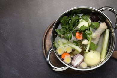 Photo of Different ingredients for cooking tasty bouillon in pot on black table, top view. Space for text