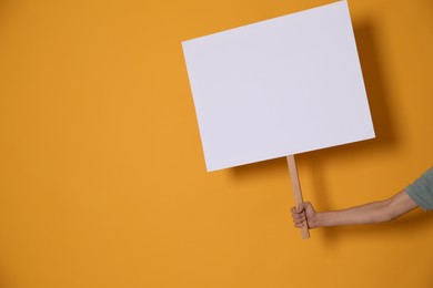 Woman holding blank sign on yellow background, closeup. Space for text