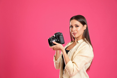 Photo of Professional photographer working on pink background in studio. Space for text