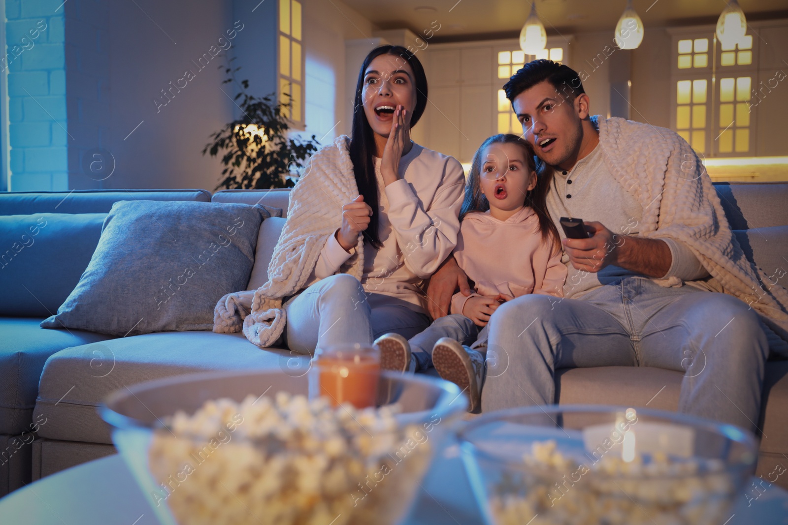 Photo of Family watching movie on sofa at night