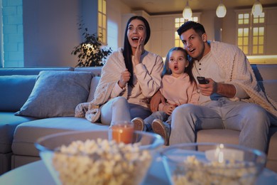 Photo of Family watching movie on sofa at night