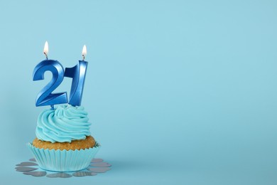 Photo of Delicious cupcake with number shaped candles on light blue background, space for text. Coming of age party - 21th birthday