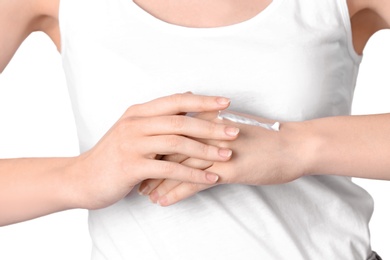 Photo of Young woman applying hand cream on white background, closeup