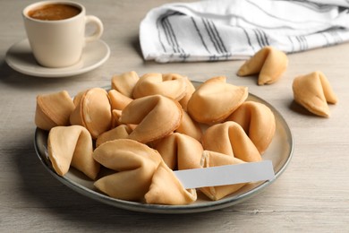 Photo of Tasty fortune cookies and paper with prediction on wooden table. Space for text