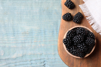 Fresh ripe blackberries on blue wooden table, flat lay. Space for text