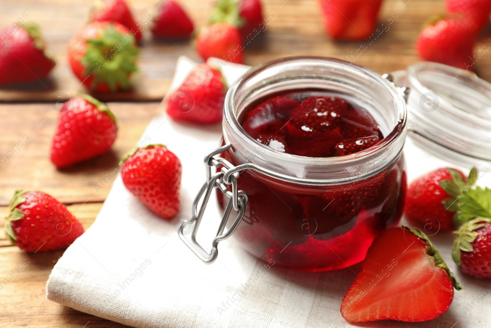 Photo of Delicious pickled strawberry jam and fresh berries on wooden table