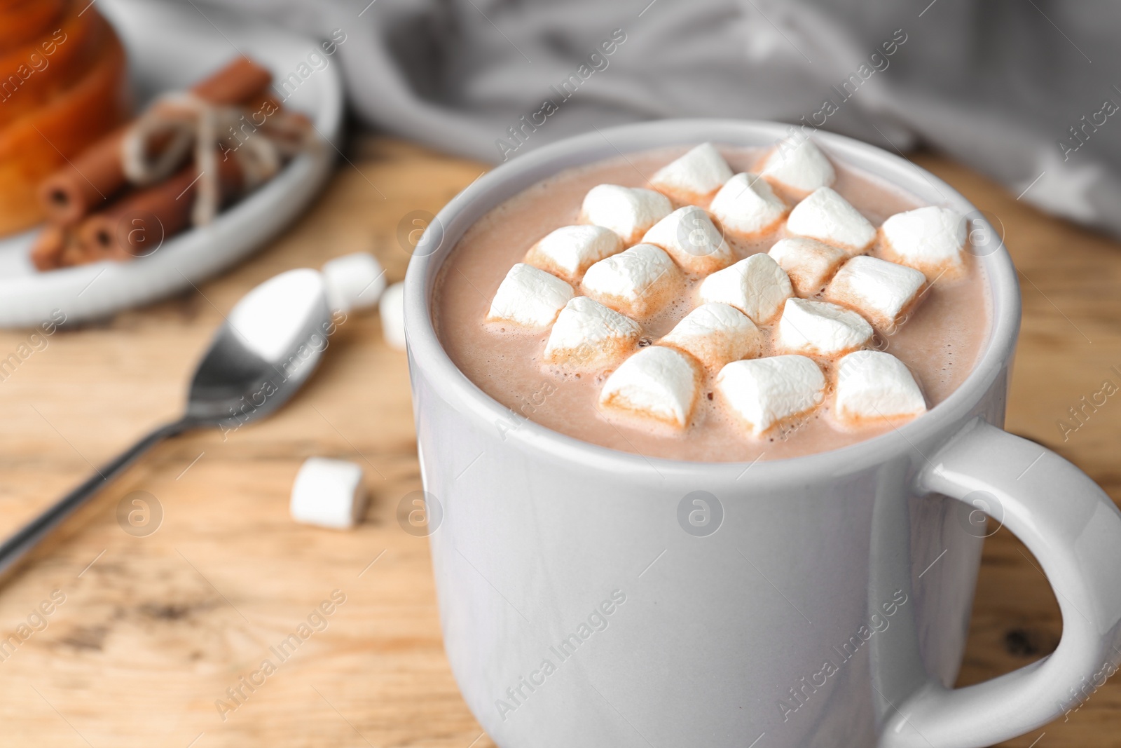 Photo of Delicious hot cocoa drink with marshmallows in cup on wooden table, closeup