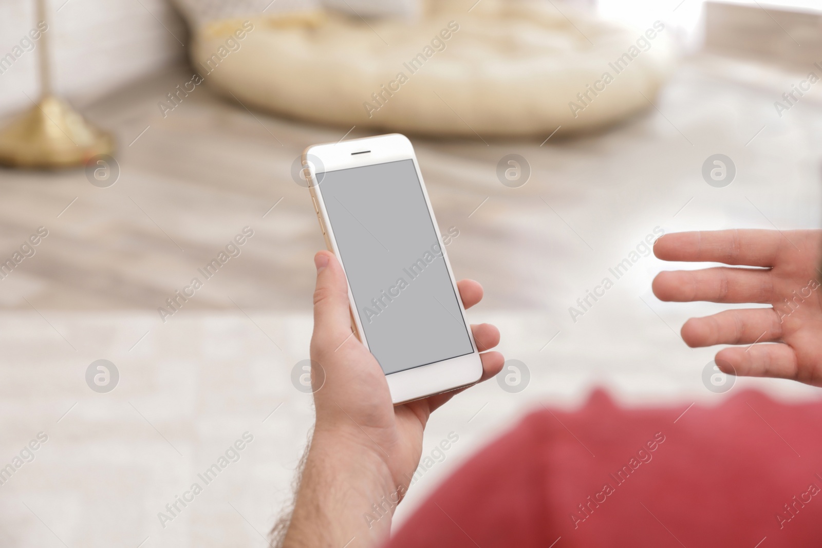 Photo of Young man using video chat on smartphone at home, closeup. Space for design