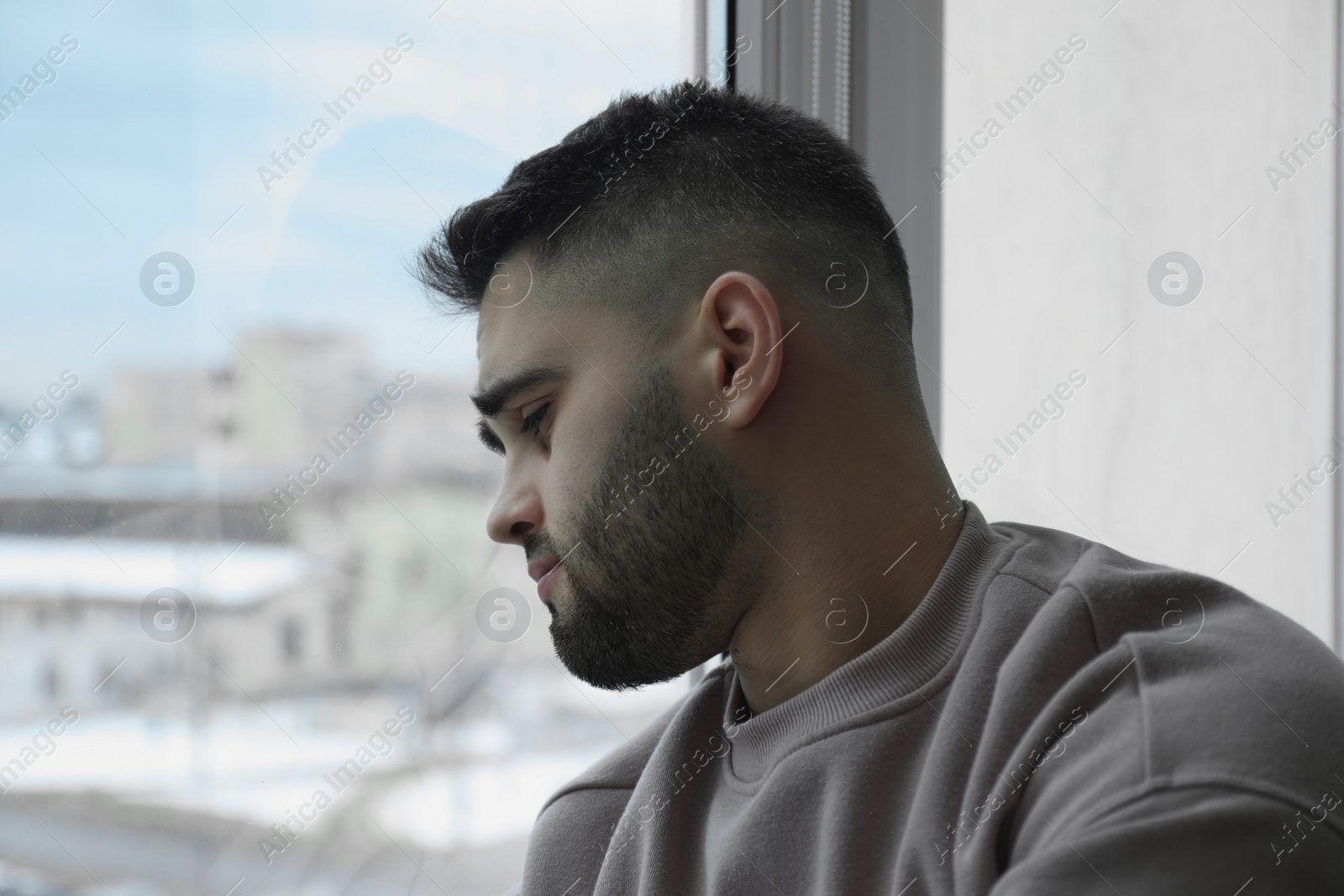 Photo of Portrait of sad man near window at home