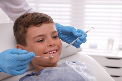 Photo of Dentist examining little boy's teeth in modern clinic