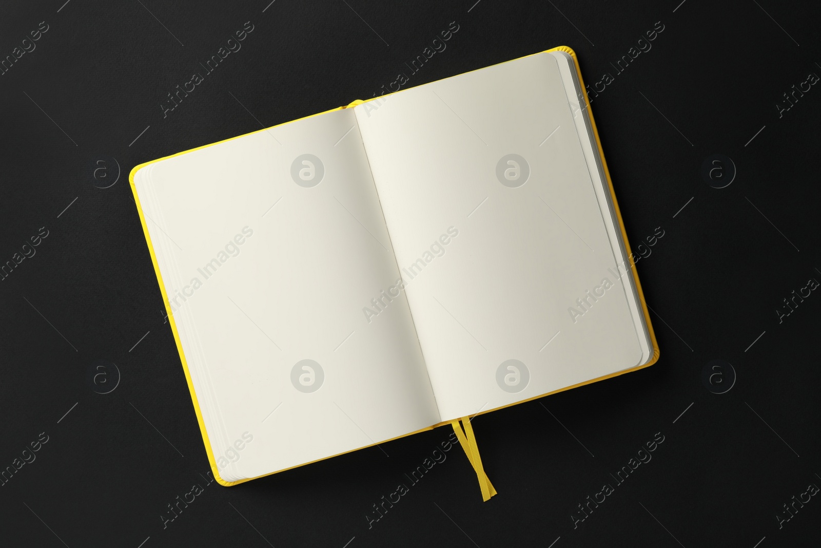 Photo of Open blank notebook on black background, top view