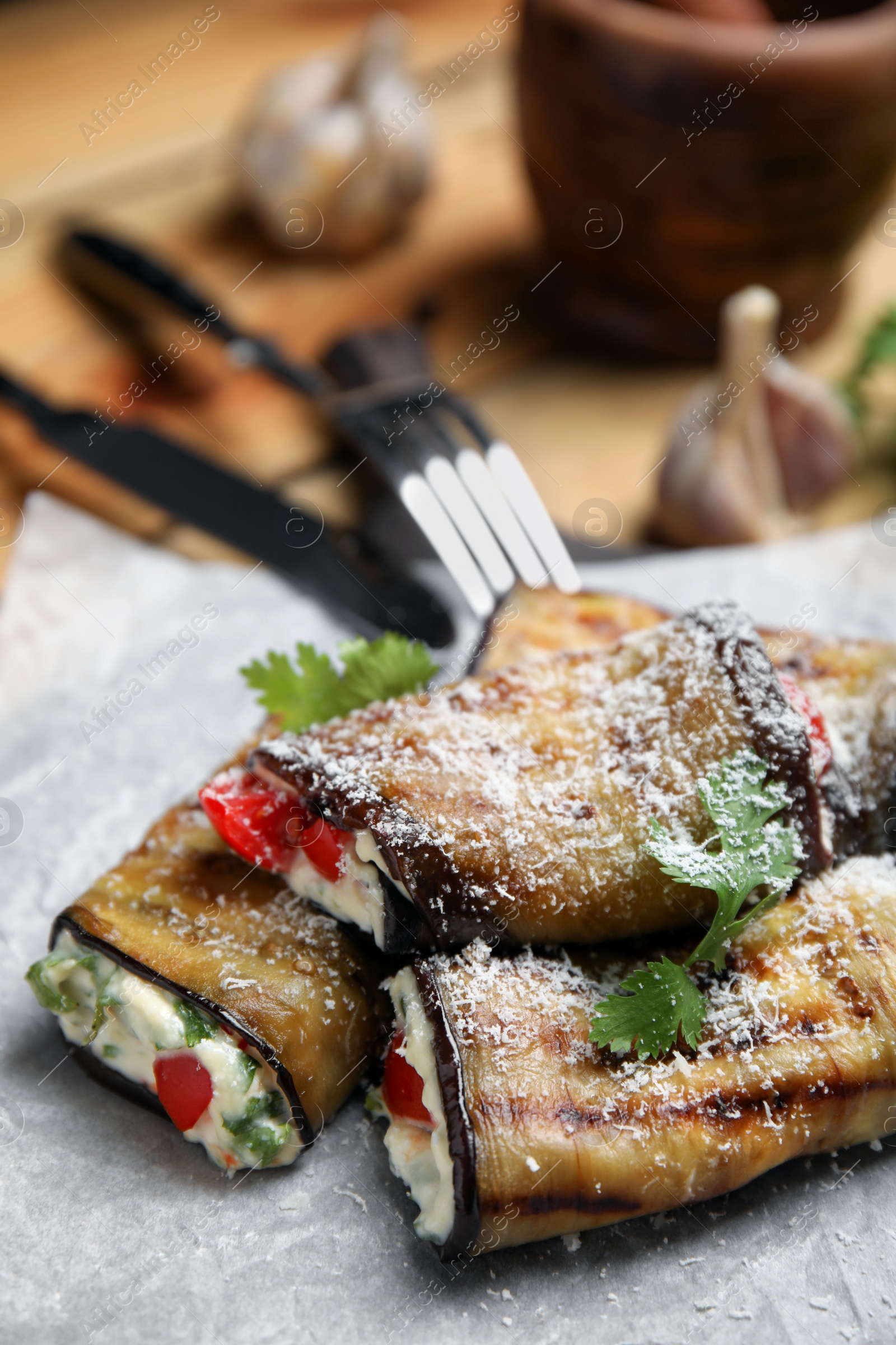 Photo of Delicious fried eggplant rolls with cheese, tomatoes and parsley on paper, closeup