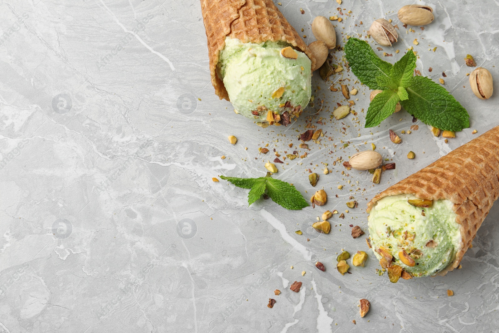 Photo of Delicious pistachio ice cream on grey marble table, flat lay. Space for text