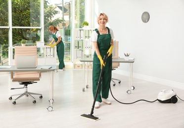 Photo of Team of janitors in uniform cleaning office