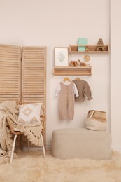 Photo of Children's room interior with stylish wooden furniture, baby clothes and decor elements
