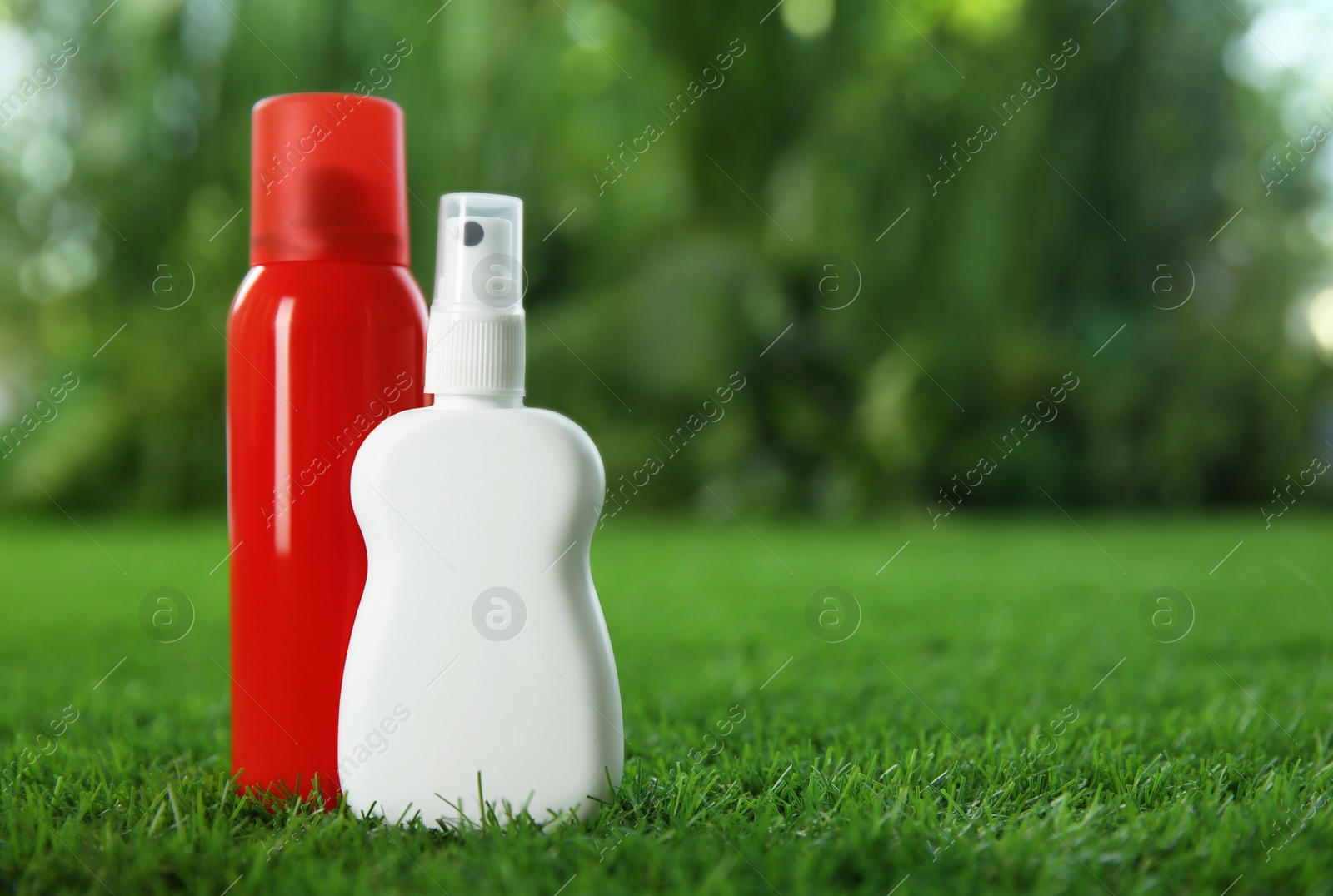 Photo of Different insect repellents on green grass. Space for text