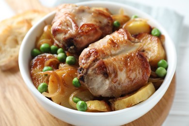 Tasty cooked rabbit with vegetables in bowl on wooden board, closeup