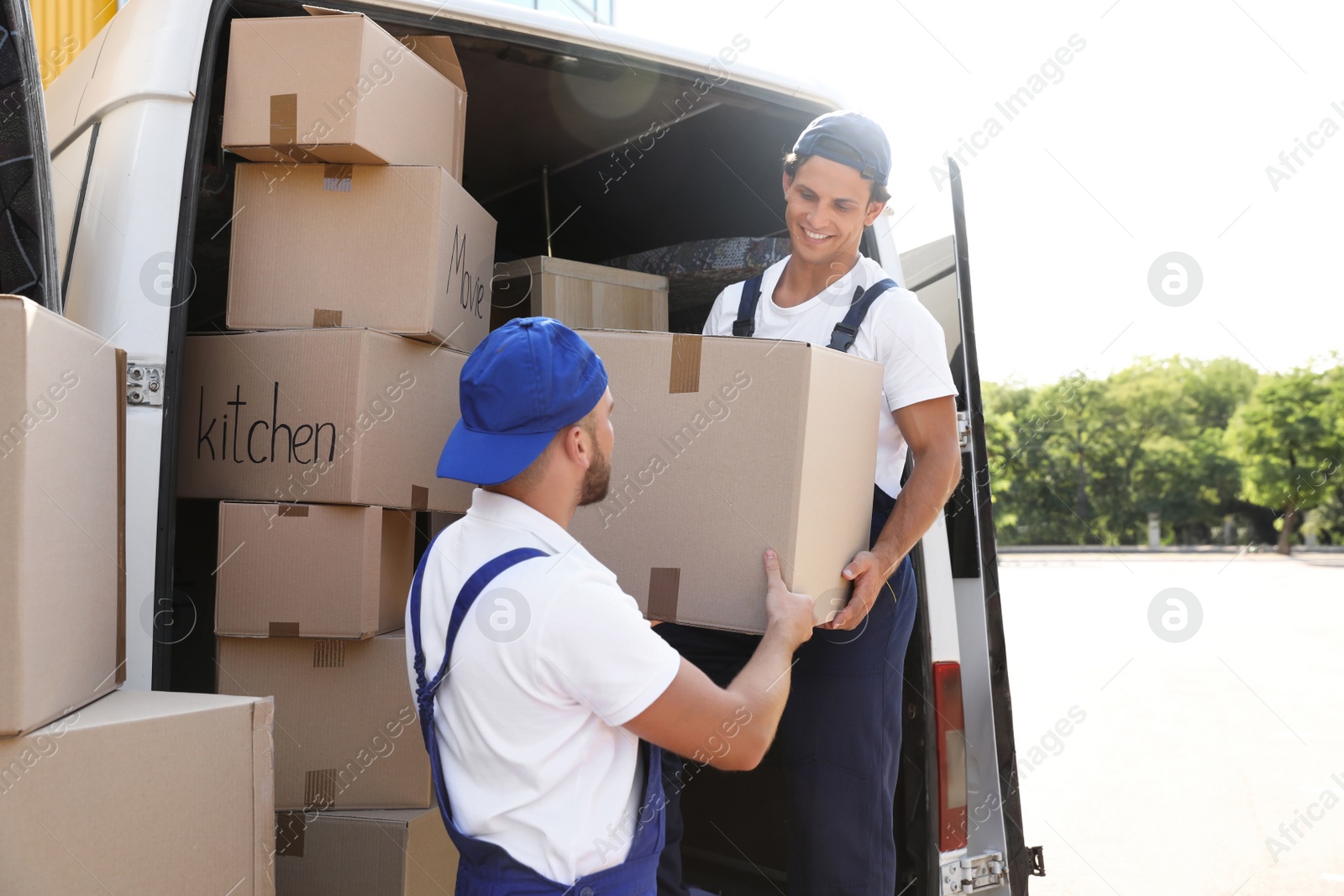 Photo of Male movers unloading boxes from van outdoors