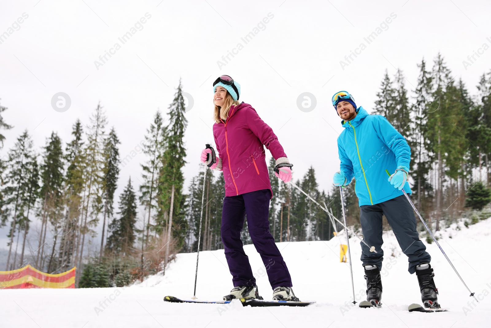 Photo of Couple of skiers on slope at resort. Winter vacation