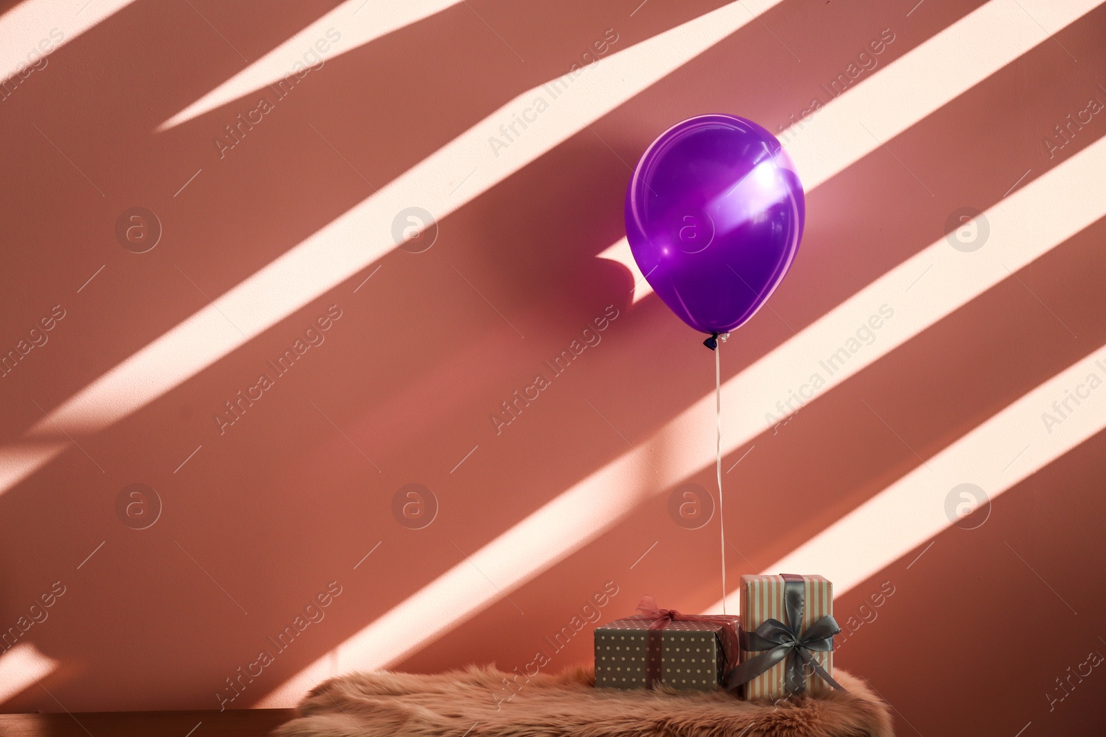 Photo of Purple balloon and gifts on table against color background