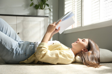 Photo of Beautiful young woman reading book at home