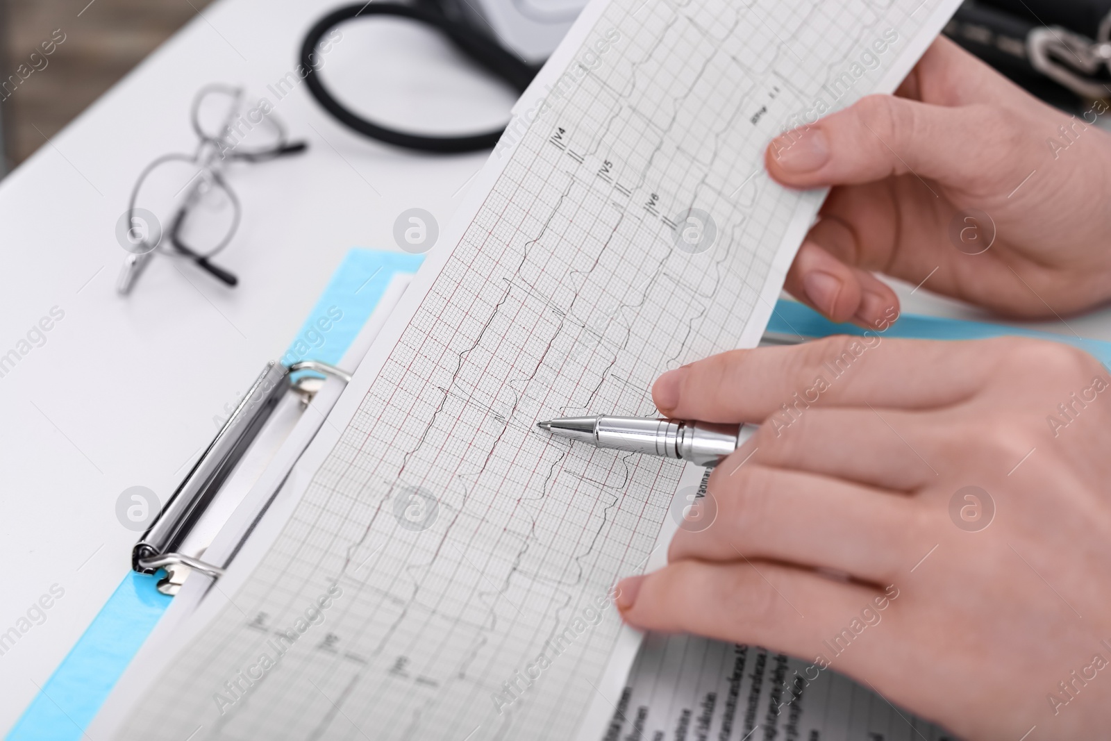 Photo of Doctor examining cardiogram at table in clinic, closeup