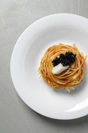 Photo of Tasty spaghetti with tomato sauce and black caviar on light grey table, top view. Exquisite presentation of pasta dish