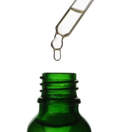 Photo of Dripping oil from pipette into glass bottle isolated on white, closeup