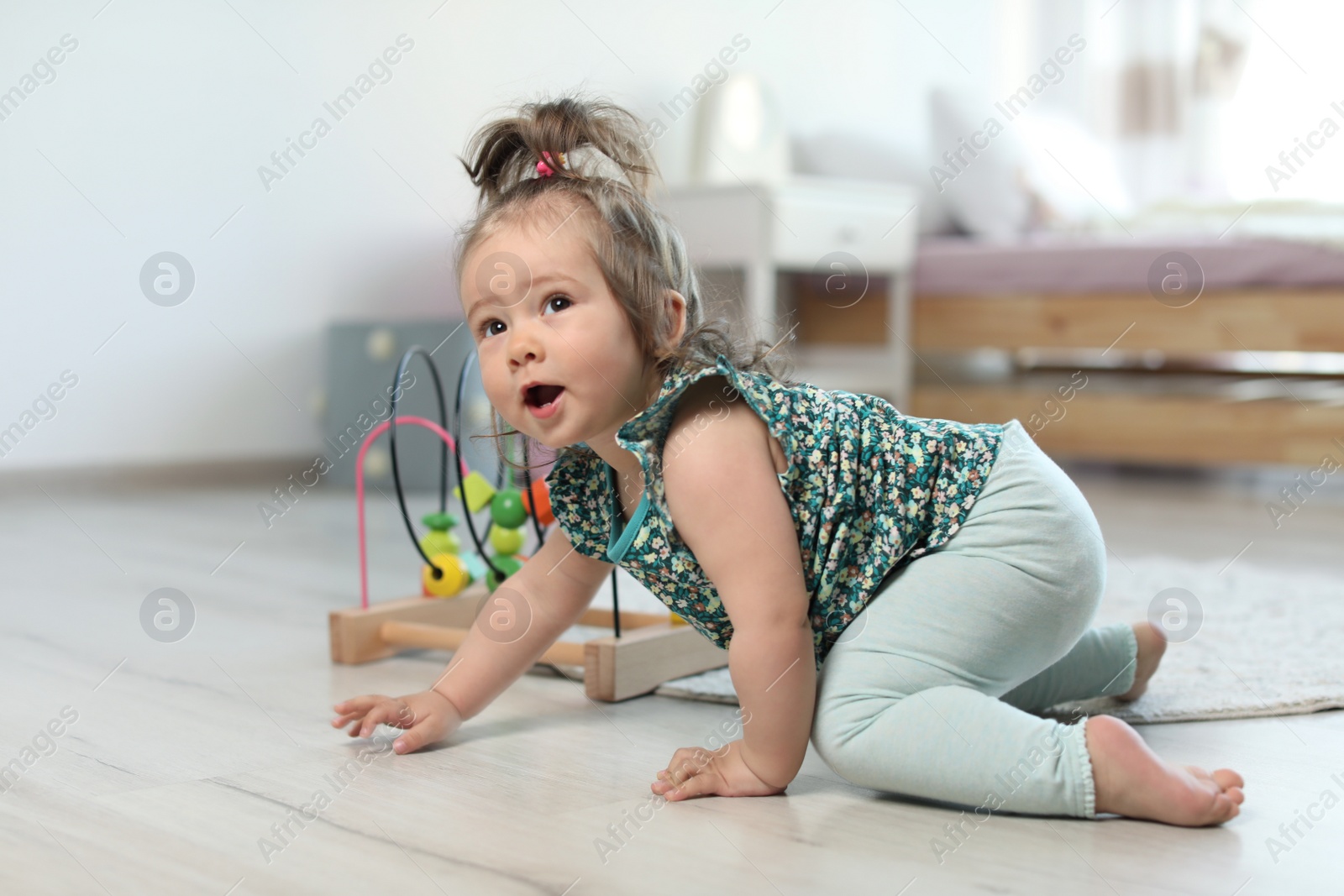 Photo of Adorable little baby girl crawling on floor in room