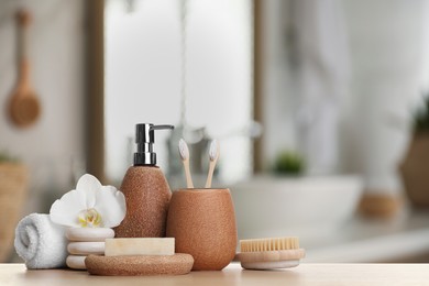 Bath accessories. Different personal care products and flower on wooden table in bathroom, space for text